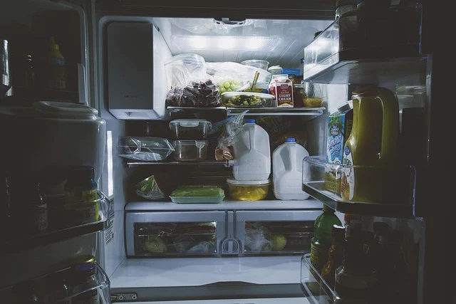 An open refrigerator filled with food and drinks, illuminated from inside.