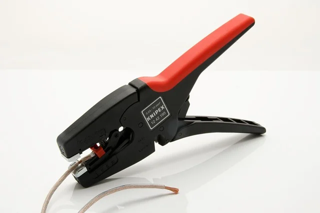 A wire stripper tool stripping insulation from a wire.