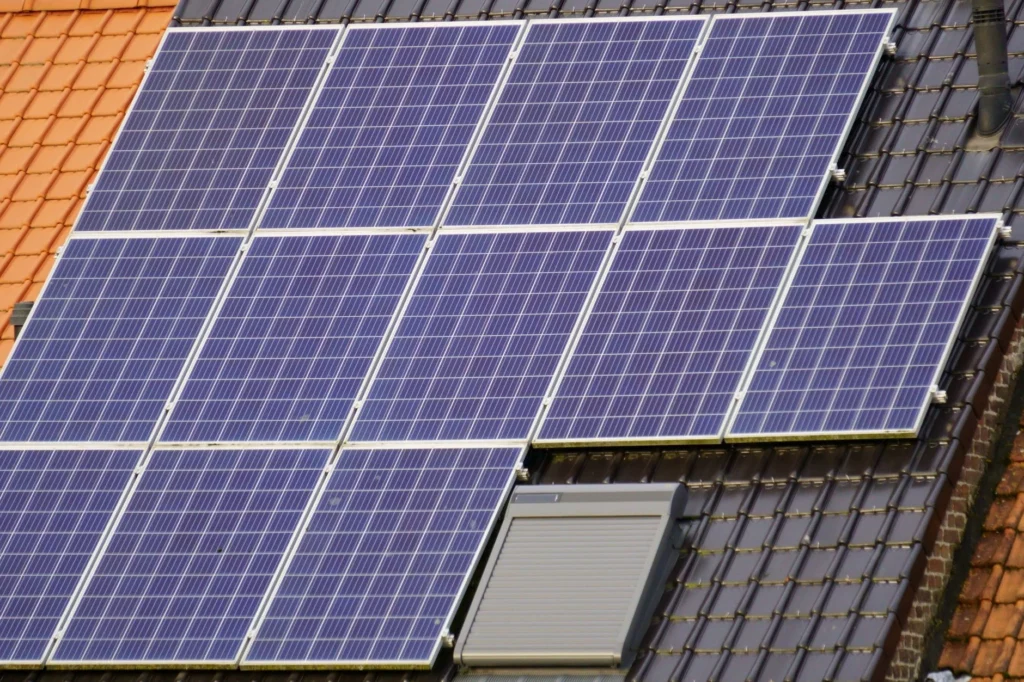 Solar panels on a dark tiled roof with a skylight.