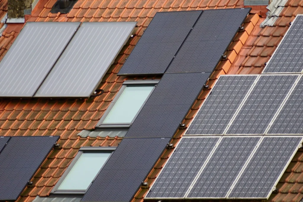 Solar panels and solar thermal collectors on a tiled roof with skylights.