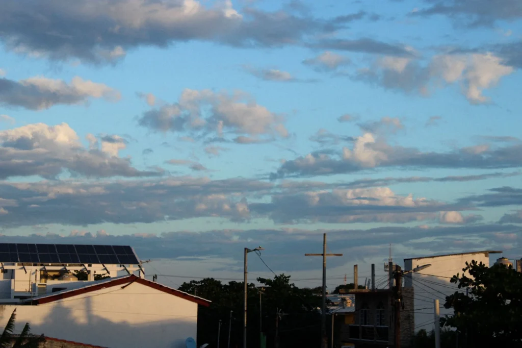 Solar panels on a rooftop under a cloudy sky.