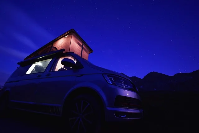 Camper van with pop-top roof under a starry night sky.