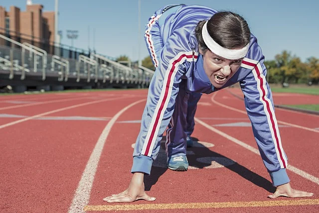 A woman in a tracksuit at the starting line of a running track.