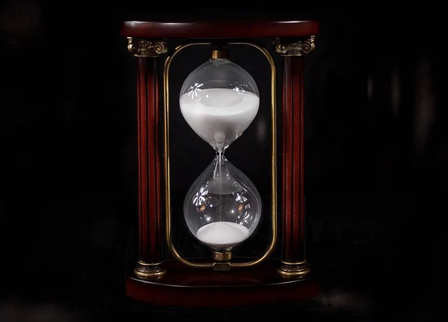 An hourglass with sand running, symbolizing time.