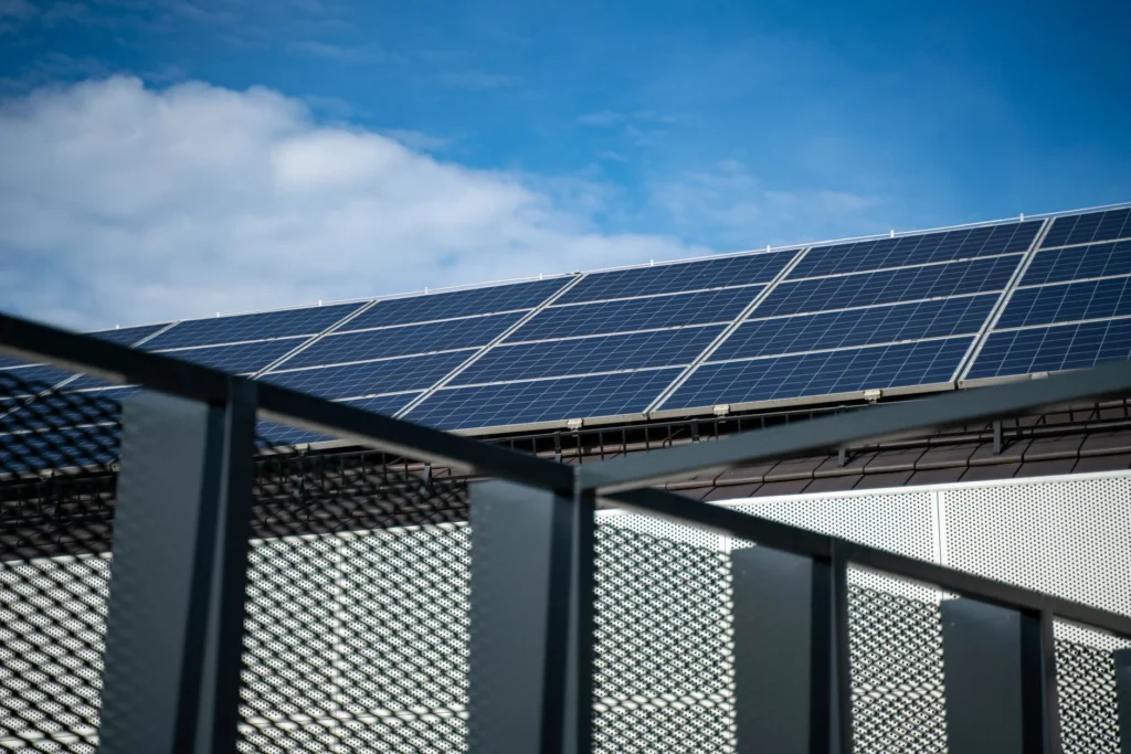 Solar panels on a roof under a blue sky with clouds