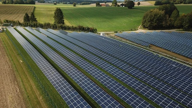 Depth of discharge: Solar panel farm in a rural landscape with fields and trees.