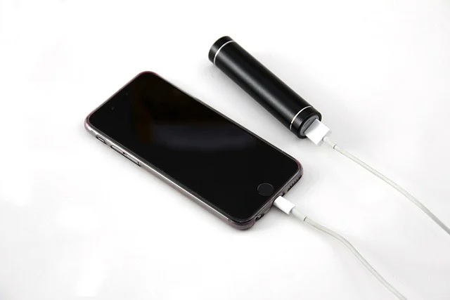 A smartphone charging from a portable power bank.