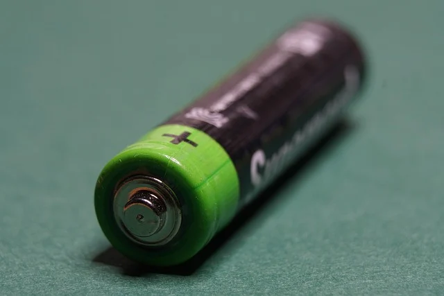 A single AA battery with a green positive end.