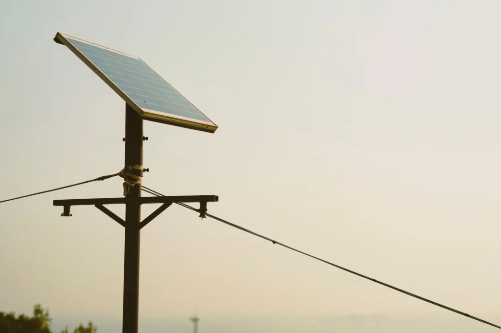 A small solar panel mounted on a pole against a hazy sky.