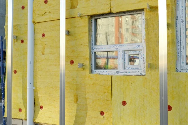 Charging lifepo4 in cold weather: Insulation being installed on the exterior of a building with windows.