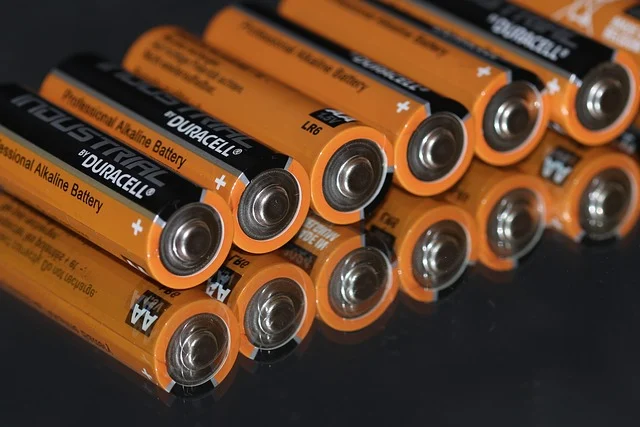 A row of Duracell AA batteries on a reflective surface.