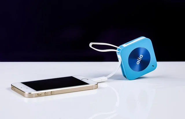 A smartphone charging from a blue portable power bank.