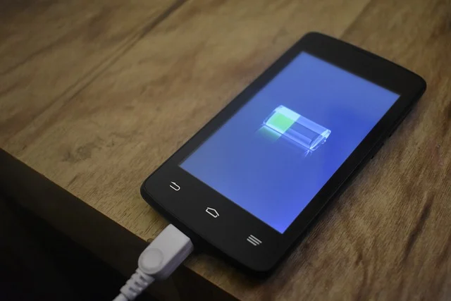 A smartphone charging, displaying a battery icon with a green charge level.