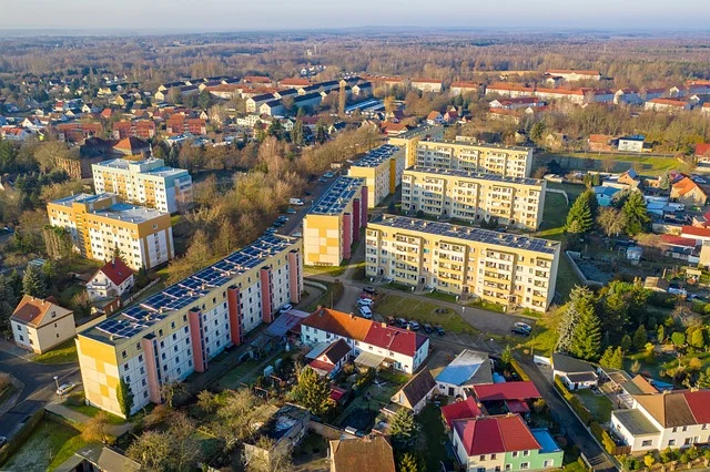 Aerial view of buildings with solar panels on roofs in a town.