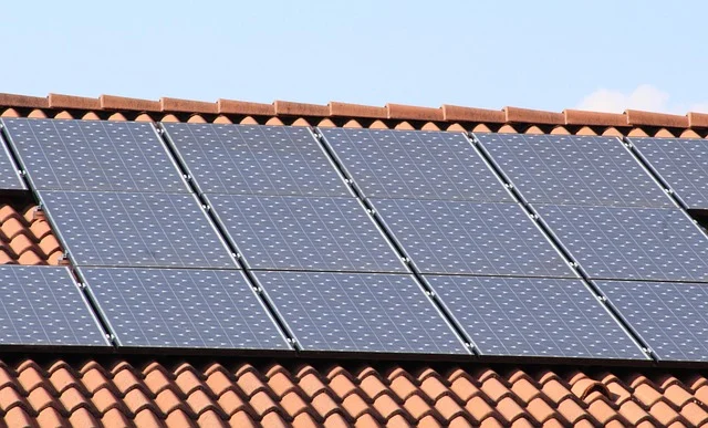 Solar panels on a terracotta tiled roof under a clear sky.